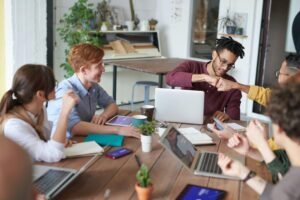 A diverse group of young professionals brainstorming around a table in a modern office environment.